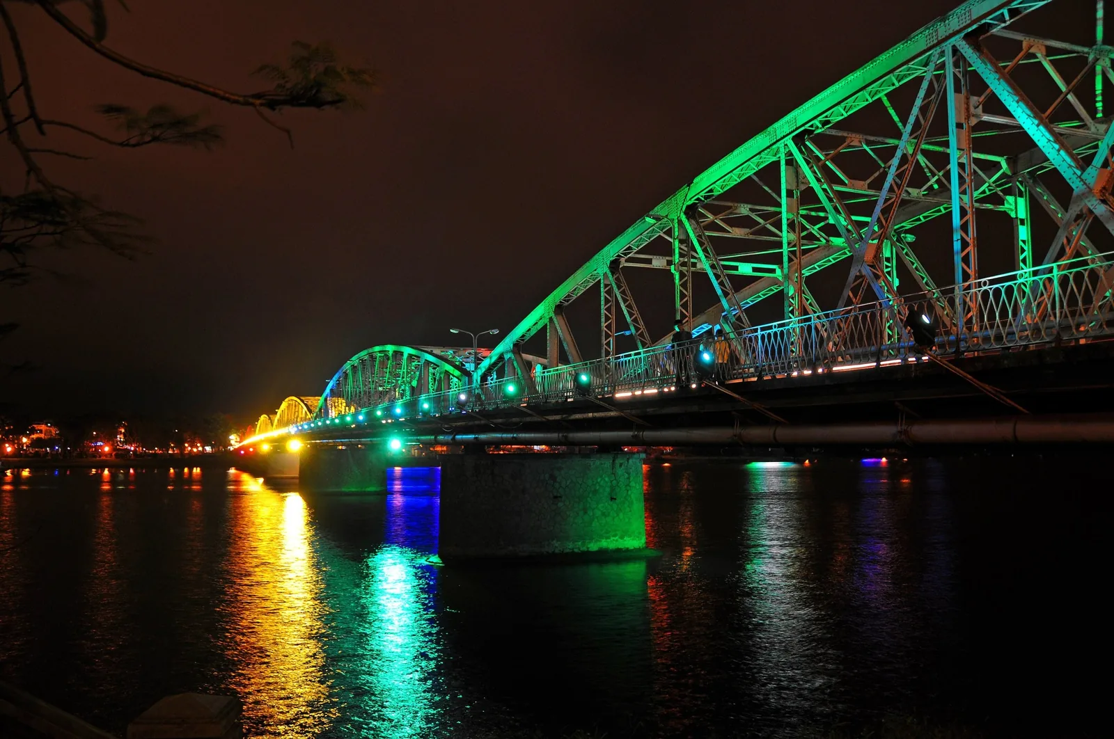 Truong Tien Bridge's steel trusses glow green at night over the Perfume River in Hue.