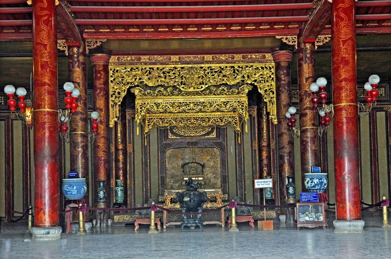 Ornate red and gold throne hall with carved canopy and lacquered columns inside the Hue Imperial City.