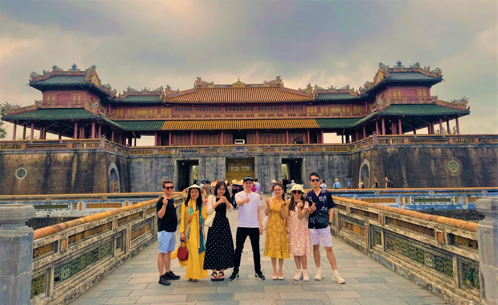Tourists pose on a stone bridge in front of the ornate Ngo Mon Gate at the Hue Imperial City.