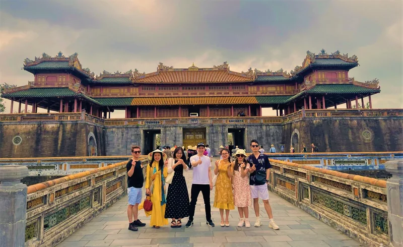 Tourists pose on a stone bridge in front of the ornate Ngo Mon Gate at the Hue Imperial City.